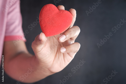  man holding red heart against black background 