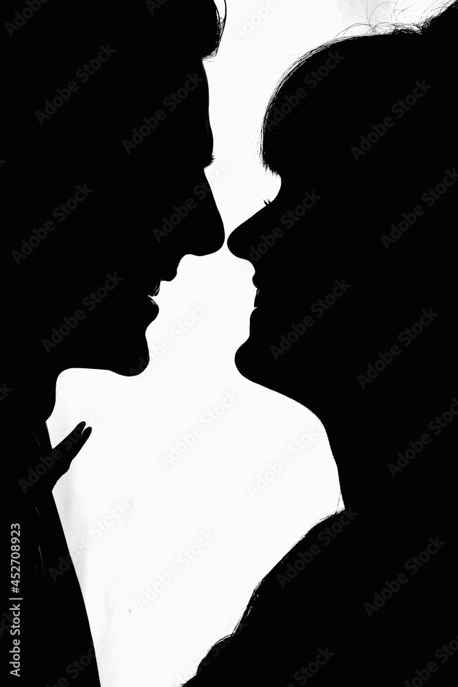 Side view of silhouettes of interracial couple in love looking at each other. Silhouette Of The Bride and Groom Standing At The Window Of Their Wedding Day.
