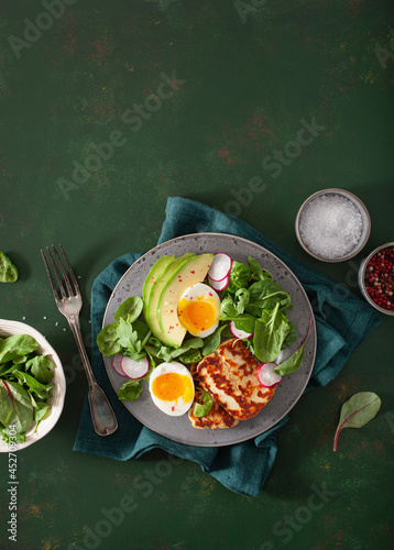 Fototapeta Naklejka Na Ścianę i Meble -  healthy keto paleo diet breakfast: boiled egg, avocado, halloumi cheese, salad leaves
