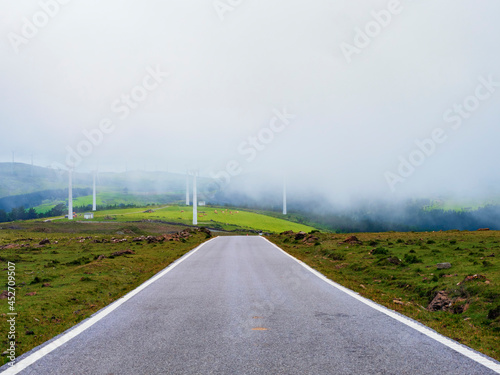 Carretera de montaña solitaria con un grupo de aerogeneradores eolicos entre la niebla  photo