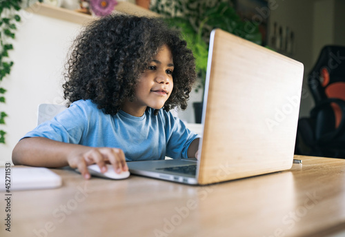 little afro boy, does homework at home with computer, back to school, homeschooling