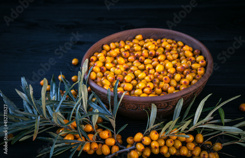 Sea buckthorn in a cup on a wooden table.