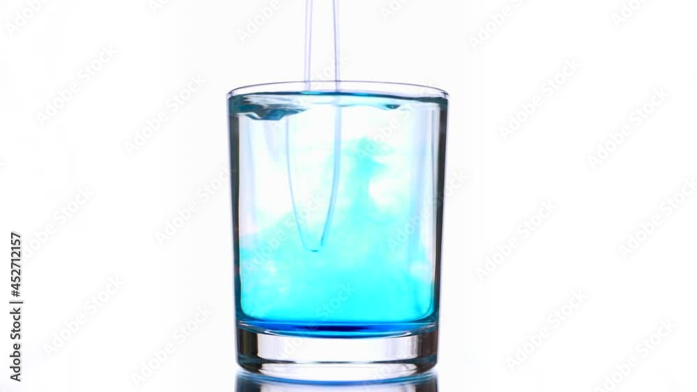Blue pigment ink leftovers of flowing patterns in a glass of light blue colored water mixing using transparent glass stick Blue pigment ink leftovers of flowing patterns in a glass of light blue colored water mixing using transparent glass stick