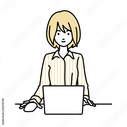 デスクで座ってPCを使っているブラウスの女性