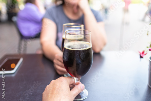 Woman and man drink beer. Friends met in a pub. Two glasses of dark beer.Two people toasting with glasses of beer.