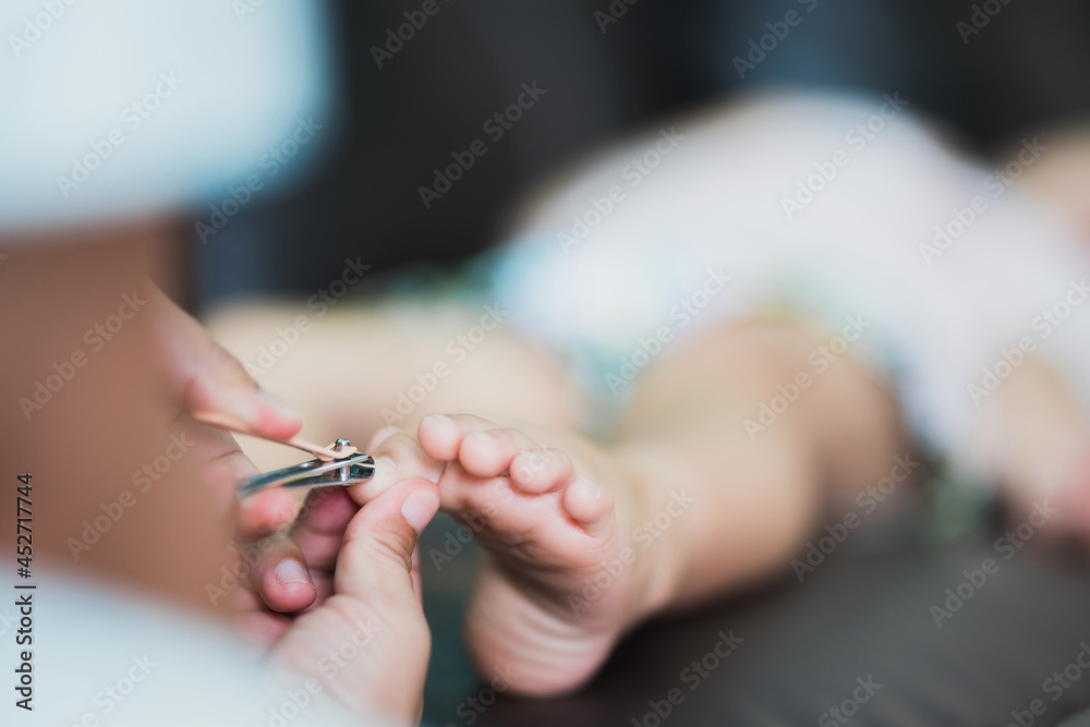 The little girl's feet were handed to his mother to cut his nails. Long nails. Take care of nails and their cleanliness.