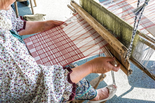 Folk Art Festival. A woman weaver makes fabric on a hand loom.