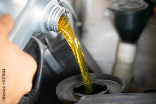 Pouring engine oil to car engine. Fresh oil poured during an oil change to a car.