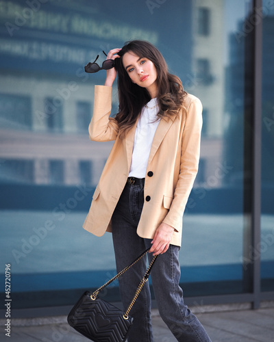 Obraz na płótnie A woman stands on the background of a glass building in a jacket w salonie
