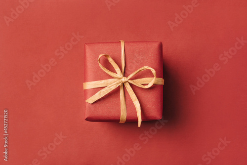 Photographie Gift boxe with brown bow on a red backdrop.
