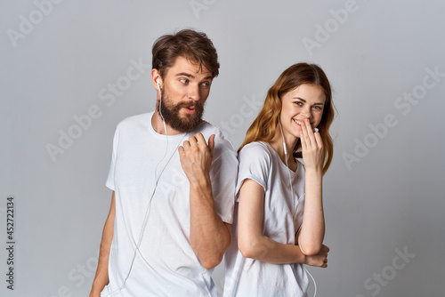 cheerful young couple in white t-shirts with headphones listening to music joy friendship