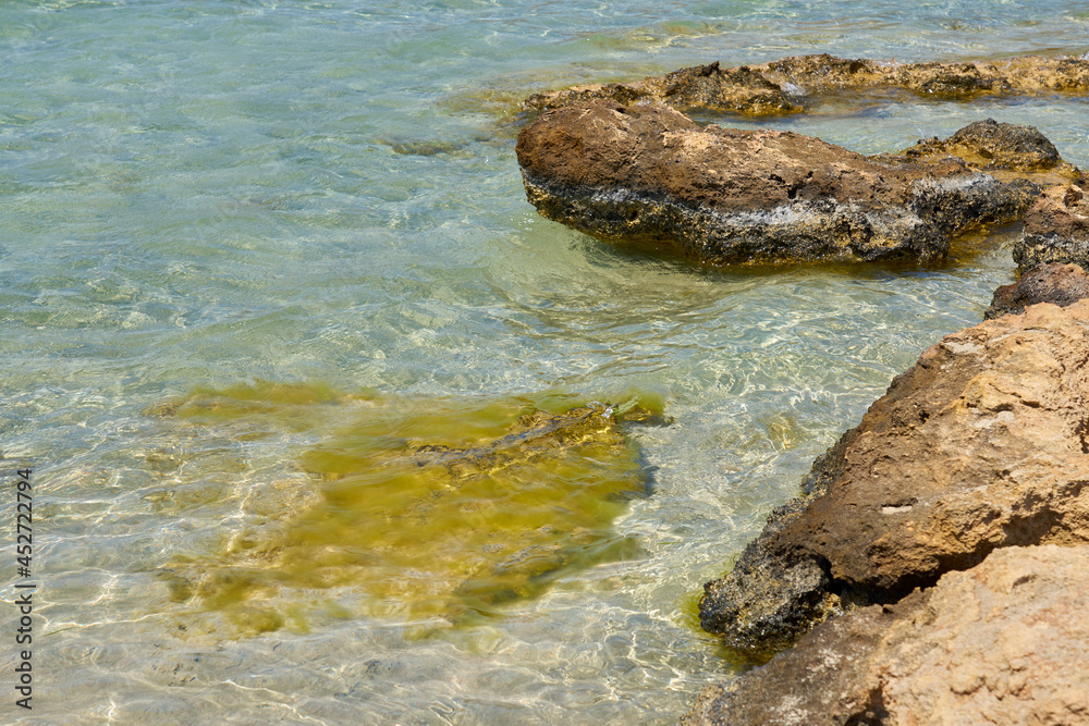 Obraz premium Surface of clear water on tropical sandy beach with stones in Crete Greece.