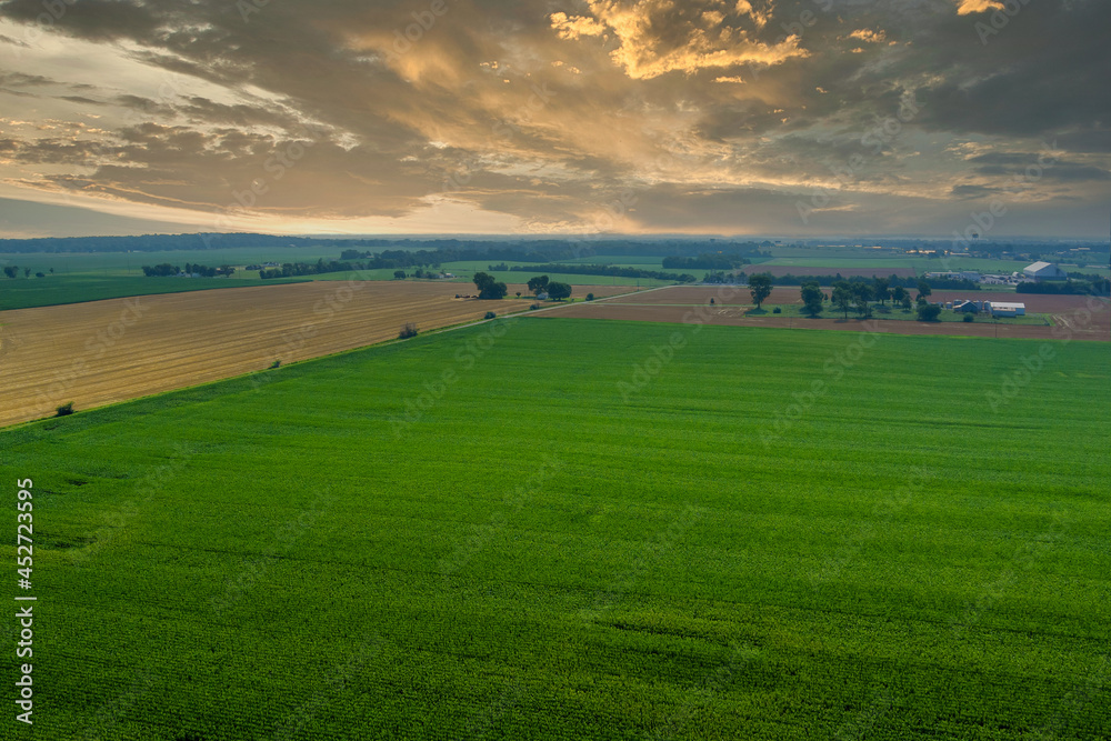 Aerial view over the village during sunset with sunlight on green fields