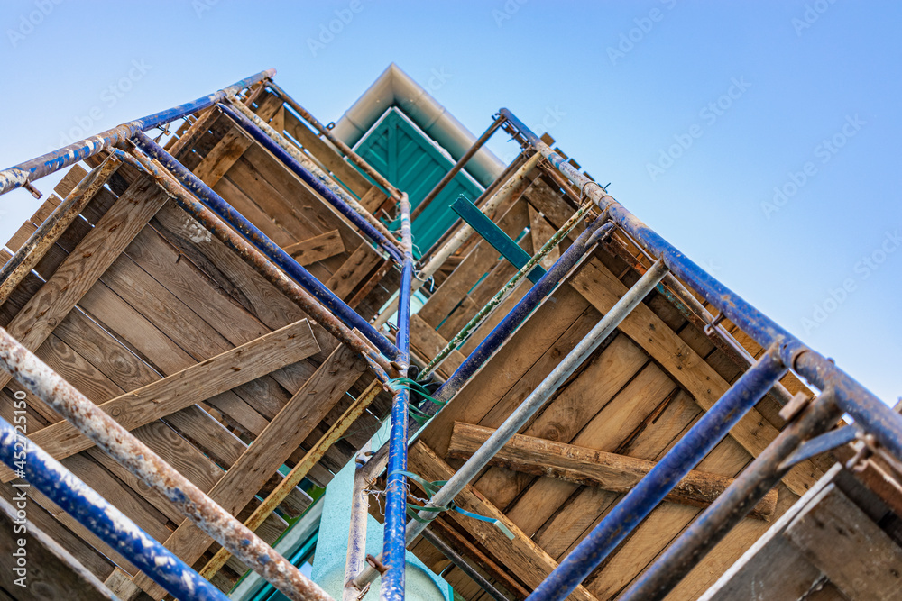 Scaffolding with wooden decks, bottom view. Performing construction work at height. Construction safety.