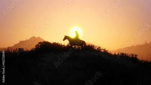 Silhouette of a cowboy on a horse at sunset, wild west mountains in the background