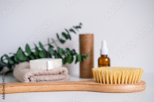 Massage wooden body brush on the background of spa items. Homemade body care. Dry lymphatic drainage massage and spa treatments.