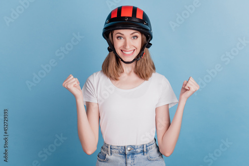 Portrait of astonished biker lady wear motorcycle helmet celebrate victory on blue background