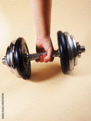 The hand holds a heavy dumbbell for bodybuilding