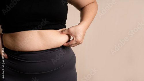 Fat woman's hand holding too much belly fat. fat belly; chubby. diet lifestyle concept for women to lose weight