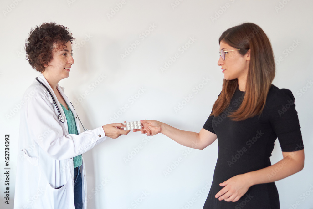A female doctor hands a patient some pills A female doctor hands a patient some pills