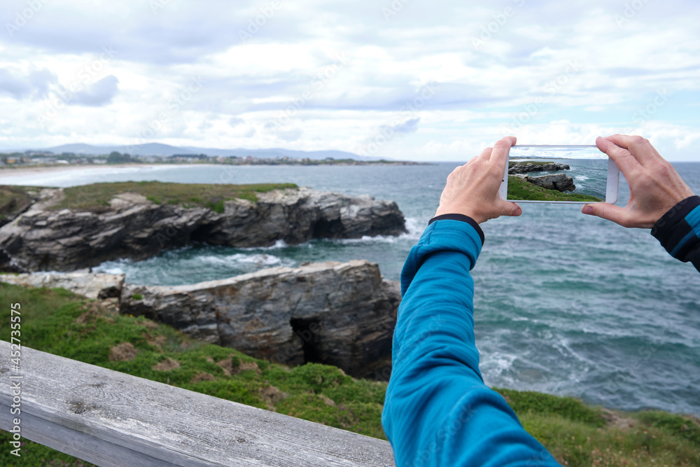 Detail of a woman's hands taking a photograph of the sea line.