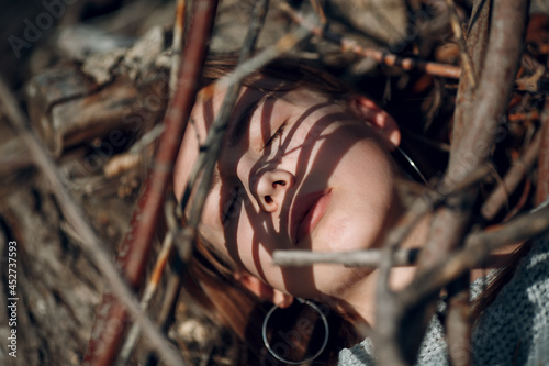 Fotografi Teenager young woman lying outdoor in the park under dry tree branches