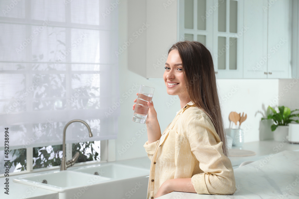 Woman with glass of tap water in kitchen Woman with glass of tap water in kitchen