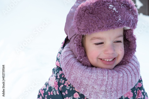 Winter, family, childhood concepts - close-up portrait authentic little preschool minor 3-4 years girl in pink hat look at camera posing smile in snowy frosty weather. happy kid face have fun outdoors