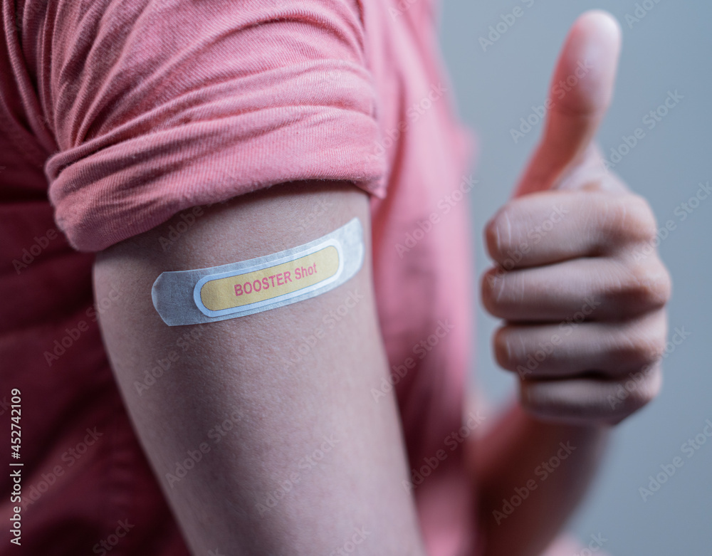 covid-19 or coronavirus vaccinated shoulder with booster shot sticker and thumbs up gesture - concept of approved coronavirus 3rd dose vaccination for immunocompromised. - obrazy, fototapety, plakaty 