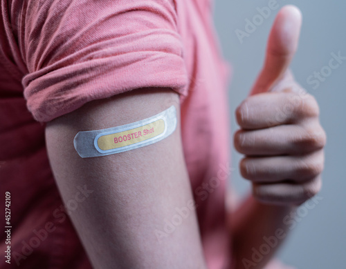 covid-19 or coronavirus vaccinated shoulder with booster shot sticker and thumbs up gesture - concept of approved coronavirus 3rd dose vaccination for immunocompromised.