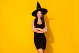 Photo of sweet optimistic witch young lady crossed arms wear black dress cap isolated on yellow color background