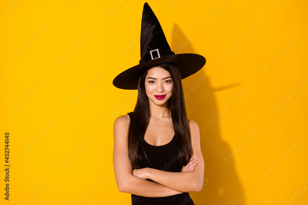 Photo of pretty witch lady crossed arms wear black dress cap isolated on yellow color background Photo of pretty witch lady crossed arms wear black dress cap isolated on yellow color background