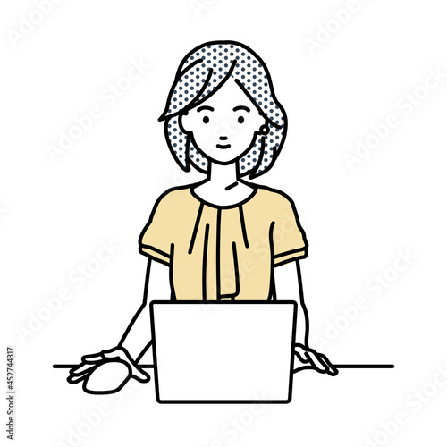 デスクで座ってPCを使っているオフィスカジュアルの女性