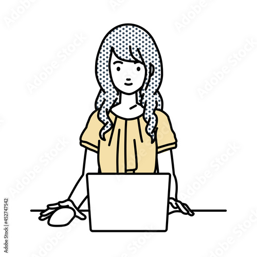 デスクで座ってPCを使っているオフィスカジュアルの女性