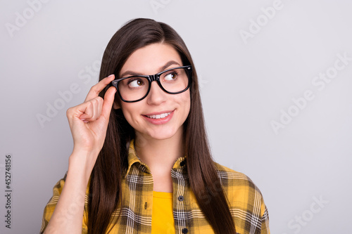 Photo of young girl happy positive smile hand touch glasses look empty space dream isolated over grey color background
