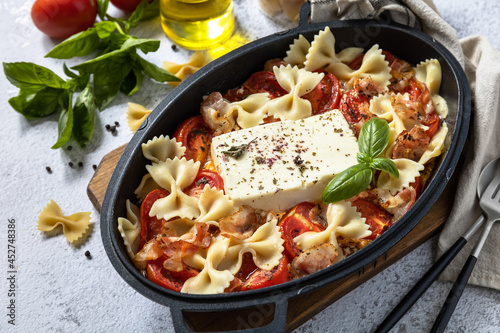 Baked feta pasta, or Tiktok pasta on gray background. Oven baked feta pasta made of tomatoes, feta cheese, garlic and herbs.