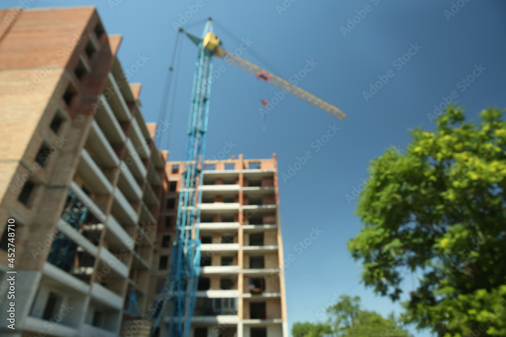 View of unfinished building and tower crane against blue sky View of unfinished building and tower crane against blue sky