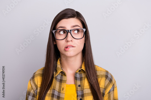 Photo of young girl bite lips worried nervous think look empty space isolated over grey color background