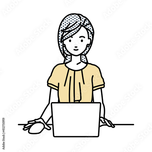 デスクで座ってPCを使っているオフィスカジュアルの女性