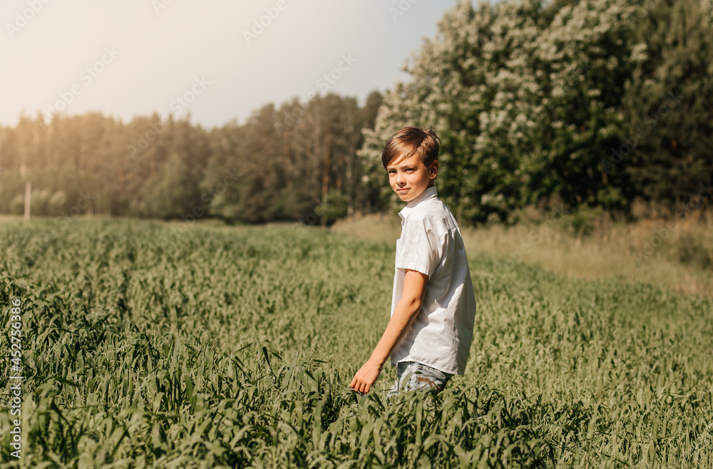 A school-age boy walks through a green field. Summer concept
