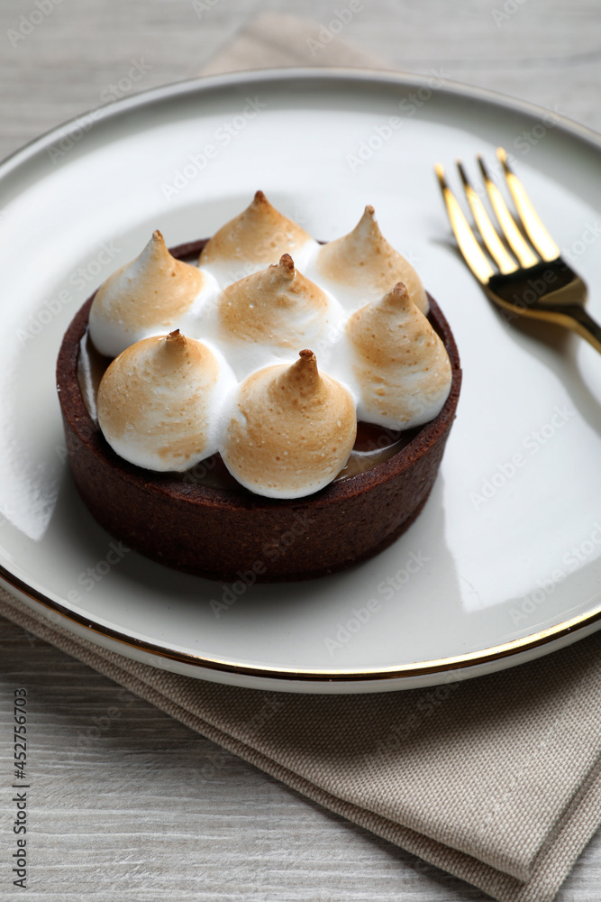 Delicious salted caramel chocolate tart with meringue served on light beige wooden table, closeup Delicious salted caramel chocolate tart with meringue served on light beige wooden table, closeup