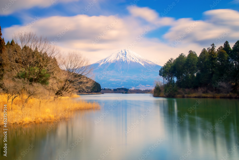 Landscape view by long exposure short of Fuji mountain at Tanuki lake with flow cloudy sky and reflection with water surface in foreground.