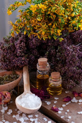 essential oil bottles with dry ingredients, wood mortar and spoon with white crystals on the wood table	