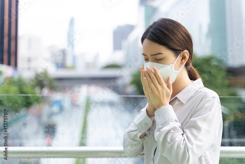 Asian female sneezing in tissue paper blowing running nose. Unhealthy woman suffering illness flu or pollution allergy.
