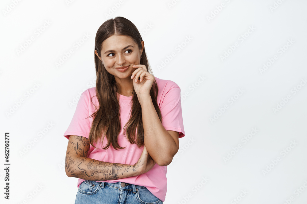 Image of young woman smiling and thinking, looking aside intrigued, has interesting idea, ponder something, white background Image of young woman smiling and thinking, looking aside intrigued, has interesting idea, ponder something, white background