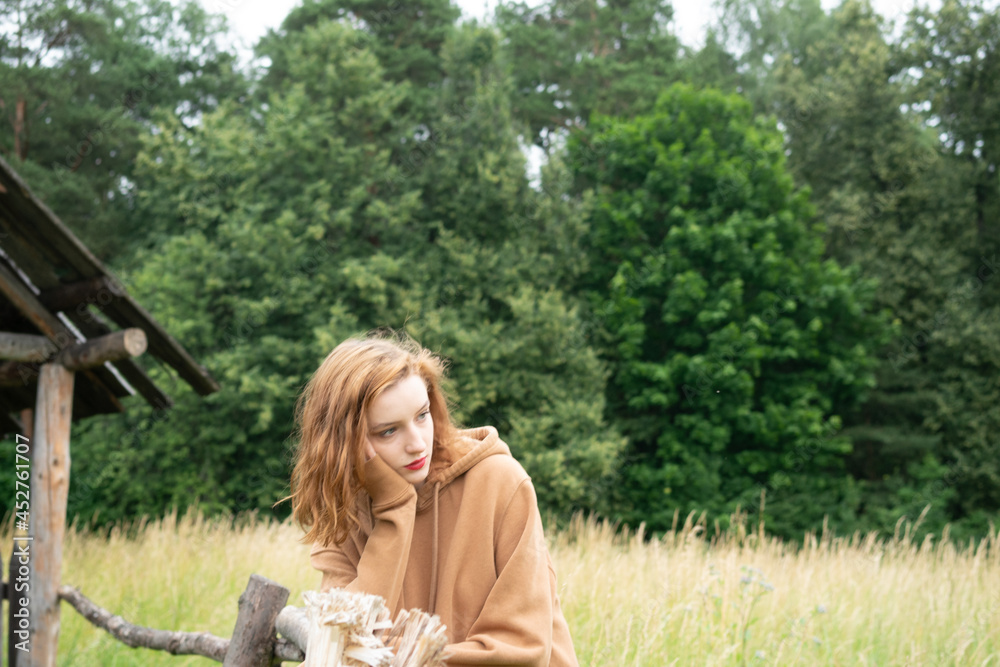 young beautiful woman posing in the summer in a field in a brown sweater young beautiful woman posing in the summer in a field in a brown sweater