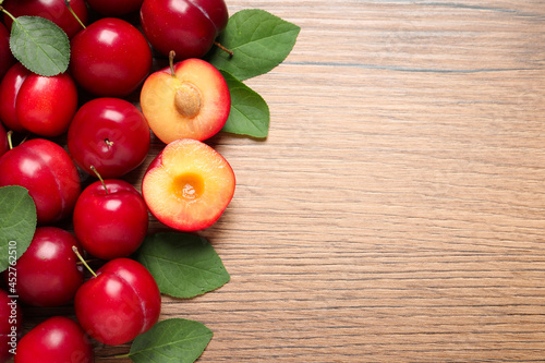 Fresh ripe cherry plums on wooden table, flat lay. Space for text
