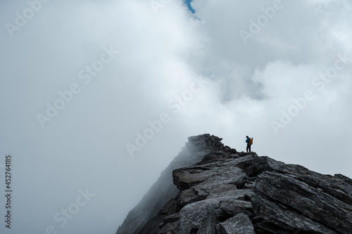 Alpinista sulla vetta di una montagna avvolta dalle nubi