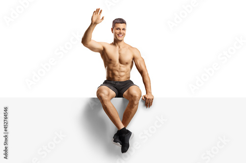 Handsome shirtless guy waving and sitting on a blank panel