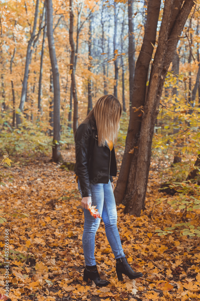 Lonely sad woman is kicking yellow leaves in autumn. Sad mood and seasonal affective disorder concept. Lonely sad woman is kicking yellow leaves in autumn. Sad mood and seasonal affective disorder concept.